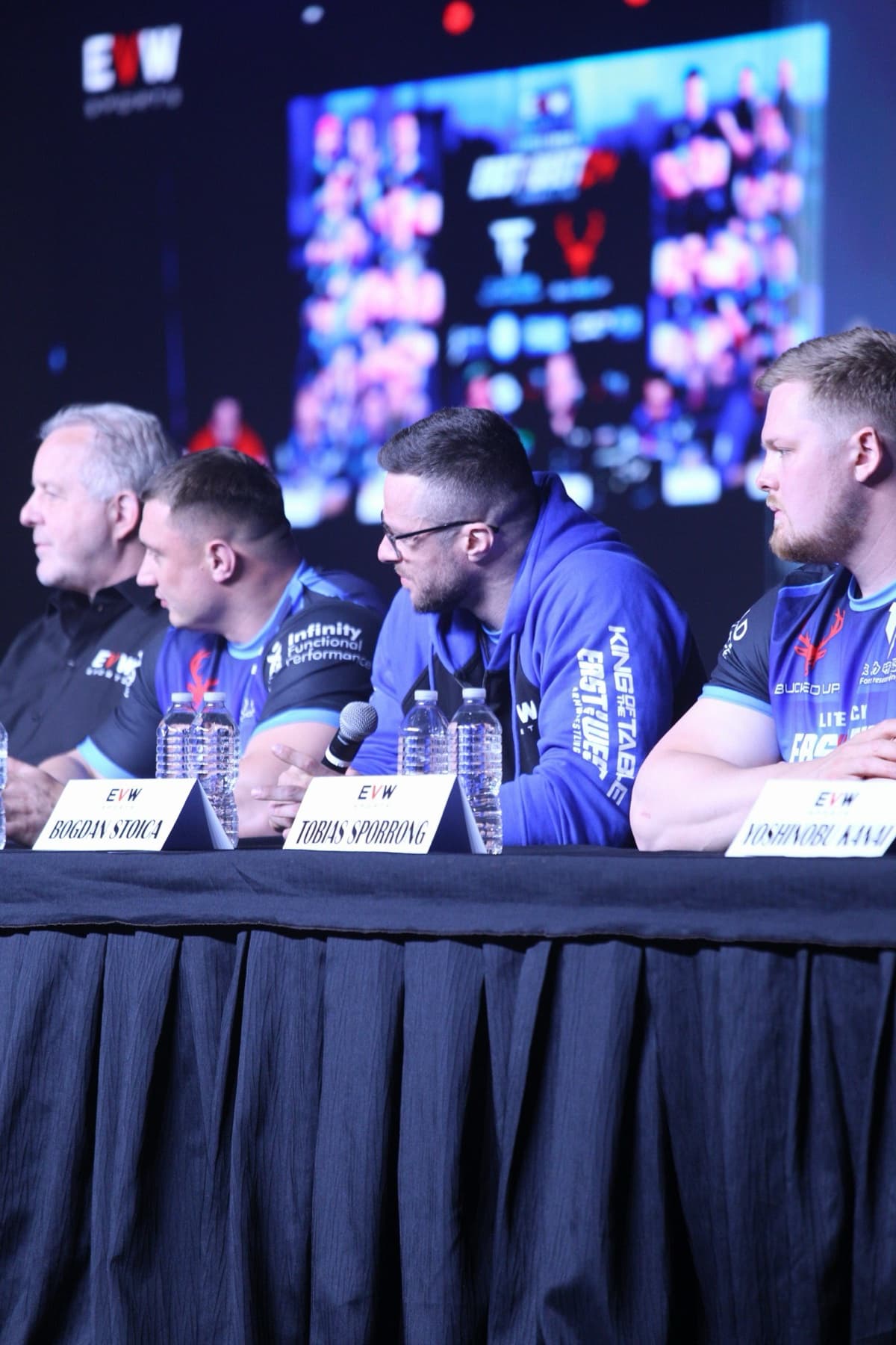 East vs West 24: competitors listen at the press conference table, name cards in front of them