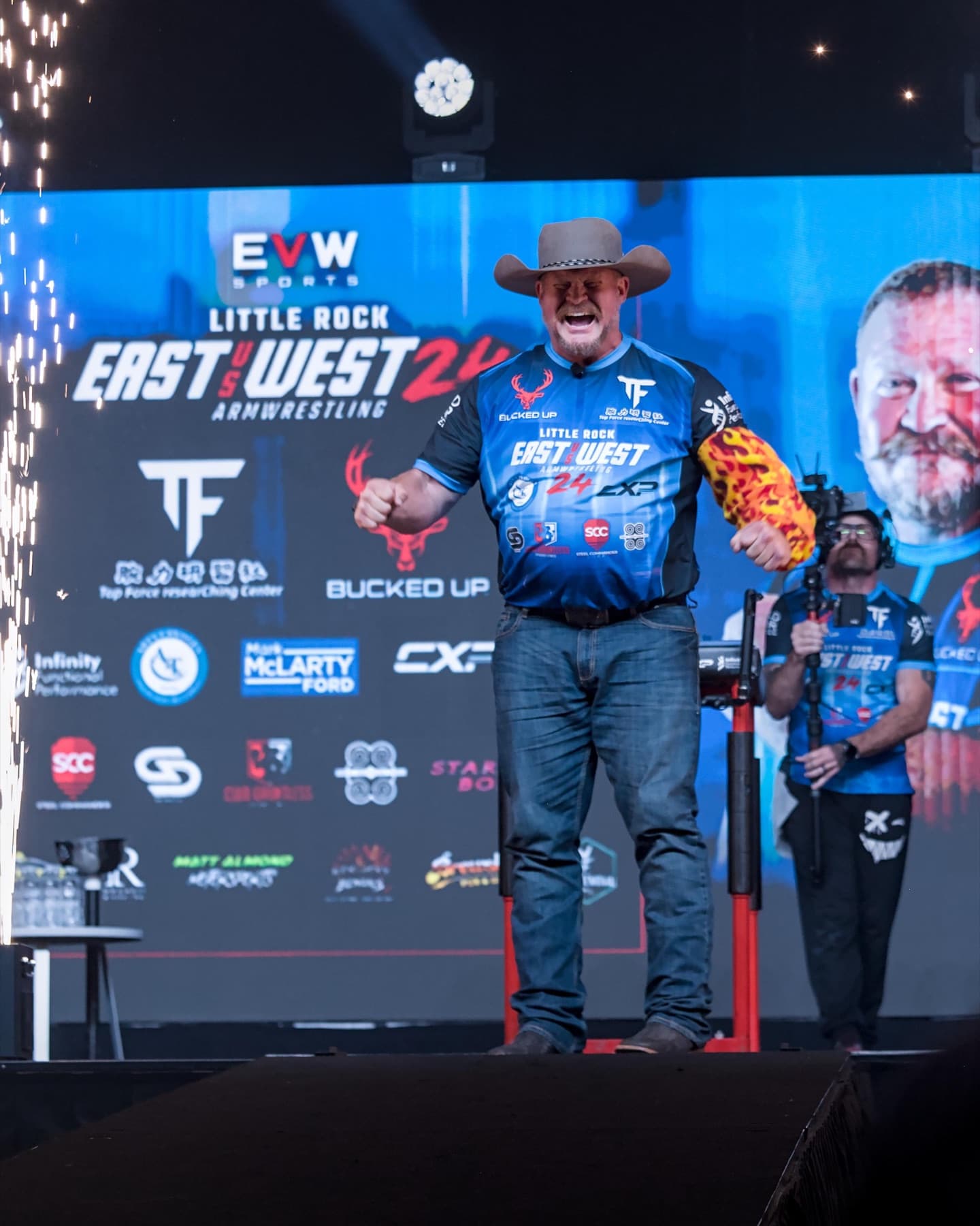 East vs West 24: a competitor celebrates on stage in front of a wall of event sponsor logos